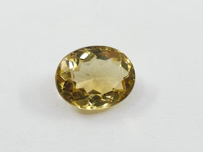 a close up of a yellow sapphire stone on a white surface