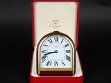 une petite horloge dans une boîte rouge posée sur une surface noire
