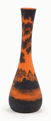 un vase noir et orange posé sur une surface blanche