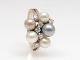 a close up of a pearl and diamond ring on a white surface