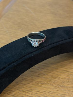 a silver ring with a diamond on top of a black case