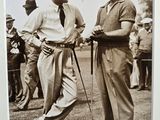 two men standing next to each other on a field with a golf club in the background