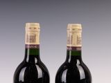 two bottles of red wine sitting next to each other on a table