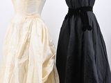 two dresses on a mannequin stand, one in black and the other in white
