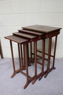 trois tables gigognes en bois disposées les unes à côté des autres sur un sol en béton