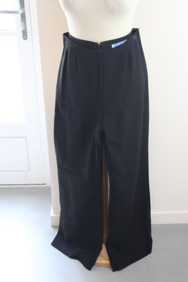 un pantalon noir sur un mannequin se tient devant une porte blanche