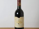 bottle of red wine sitting on a wooden table with a white wall in the background
