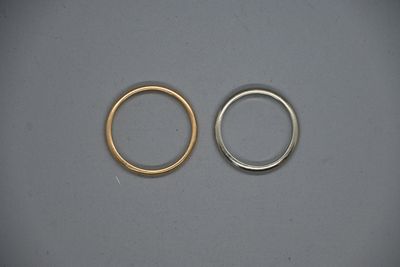 deux bagues en or et en argent posées côte à côte sur une surface grise