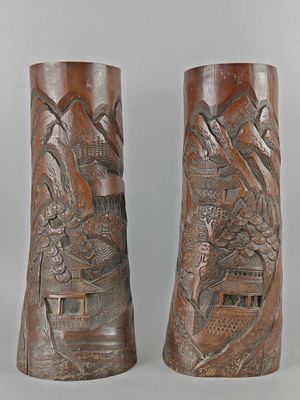 Il s'agit de deux vases ornés de sculptures, posés sur une table.