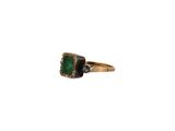 a close up of a ring with a green stone on it