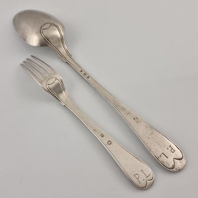 two silver spoons and a fork on a white surface