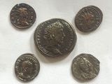 six ancient roman coins are arranged in a circle on a white surface