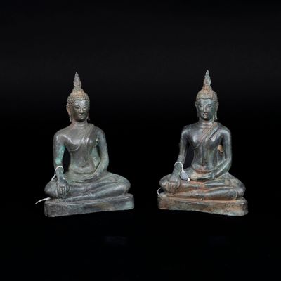 two statues of buddhas are sitting on a black surface