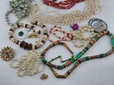 many different types of necklaces and bracelets on the table