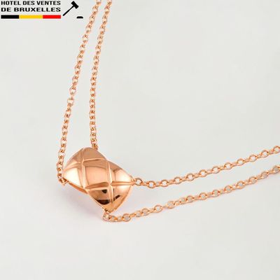 gros plan d'un collier en or sur une surface blanche