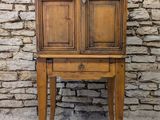 une vieille armoire en bois posée sur une table près d'un mur de briques