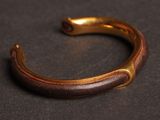 a close up of a gold and brown bracelet on a black surface