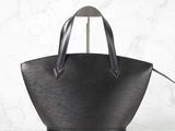 a black leather tote bag with a metal handle on a marble surface