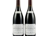 two bottles of wine sitting next to each other on a white surface