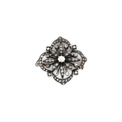 un gros plan d'une broche en forme de fleur sur fond blanc