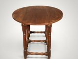 an old wooden table with a round top and turned legs