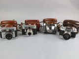 four old cameras are lined up on a white surface