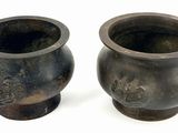 two vases sitting next to each other on a white surface