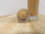 a bottle of liquid sitting on a table next to a cup of liquid