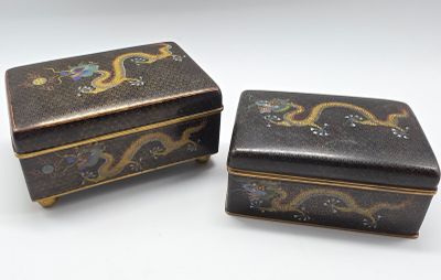 une paire de boîtes décorées de noir et d'or posées sur une surface blanche
