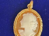 un gros plan d'un pendentif camée doré et blanc sur un fond bleu