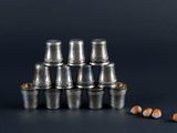 a stack of silver cups with pencils next to them