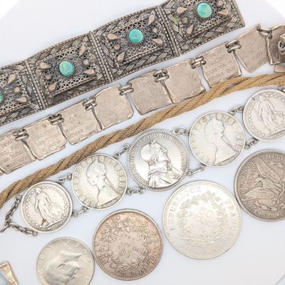 plusieurs types de pièces et de bracelets en argent posés sur un fond blanc