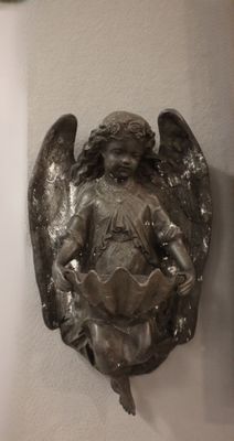 a statue of an angel on the wall next to a clock