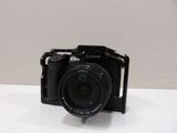 a black camera sitting on a table with a white background