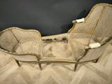 an antique wicker chaise with a curved back and a curved seat