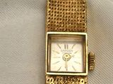 a close up of a gold watch on a white cloth