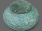 a blue vase with a green lid sitting on a gray surface
