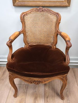 an old chair with a cane back and a brown upholstered seat
