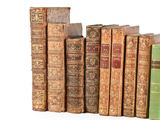 several old books are lined up in a row on a white surface
