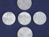 four silver coins on a blue cloth with a picture of a train in the background