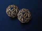 two pairs of chanel earrings on a blue surface