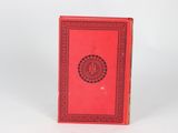a red book sitting on top of a table next to a white wall
