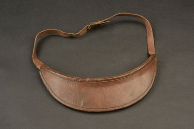 un vieux sac à main en cuir muni d'une bandoulière, posé sur une surface noire