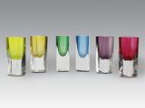 quatre verres à shot de couleurs différentes sont alignés en rangée