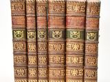 six vieux livres sont alignés sur une surface blanche