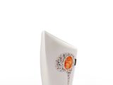 a white vase with an orange flower on it