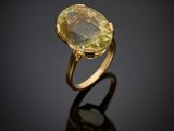 a gold ring with an oval yellow sapphire stone on a black surface