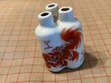 un vase blanc orné d'un poisson rouge, posé sur une table