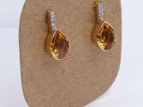 pair of yellow sapphire and diamond earrings on display on cardboard board