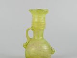 yellow glass vase with handle and handles on a white surface
